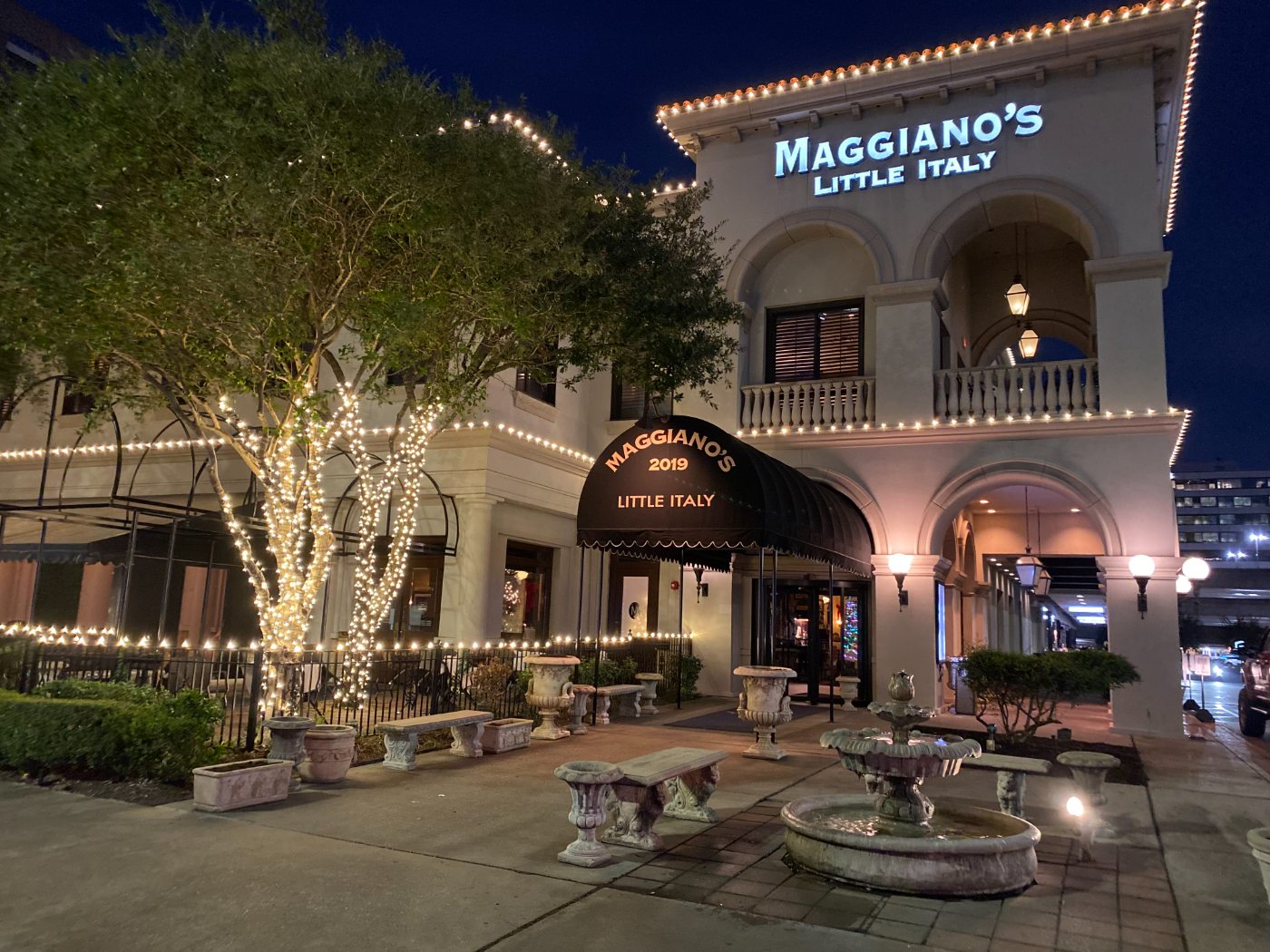Restaurant front with wrapped trees, lit awnings and a warm white cornice