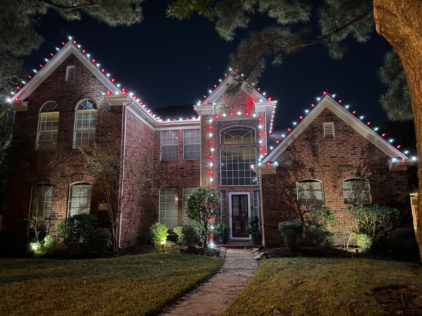 Rented commercial-grade C9 bulbs in red and white along a brick roofline
