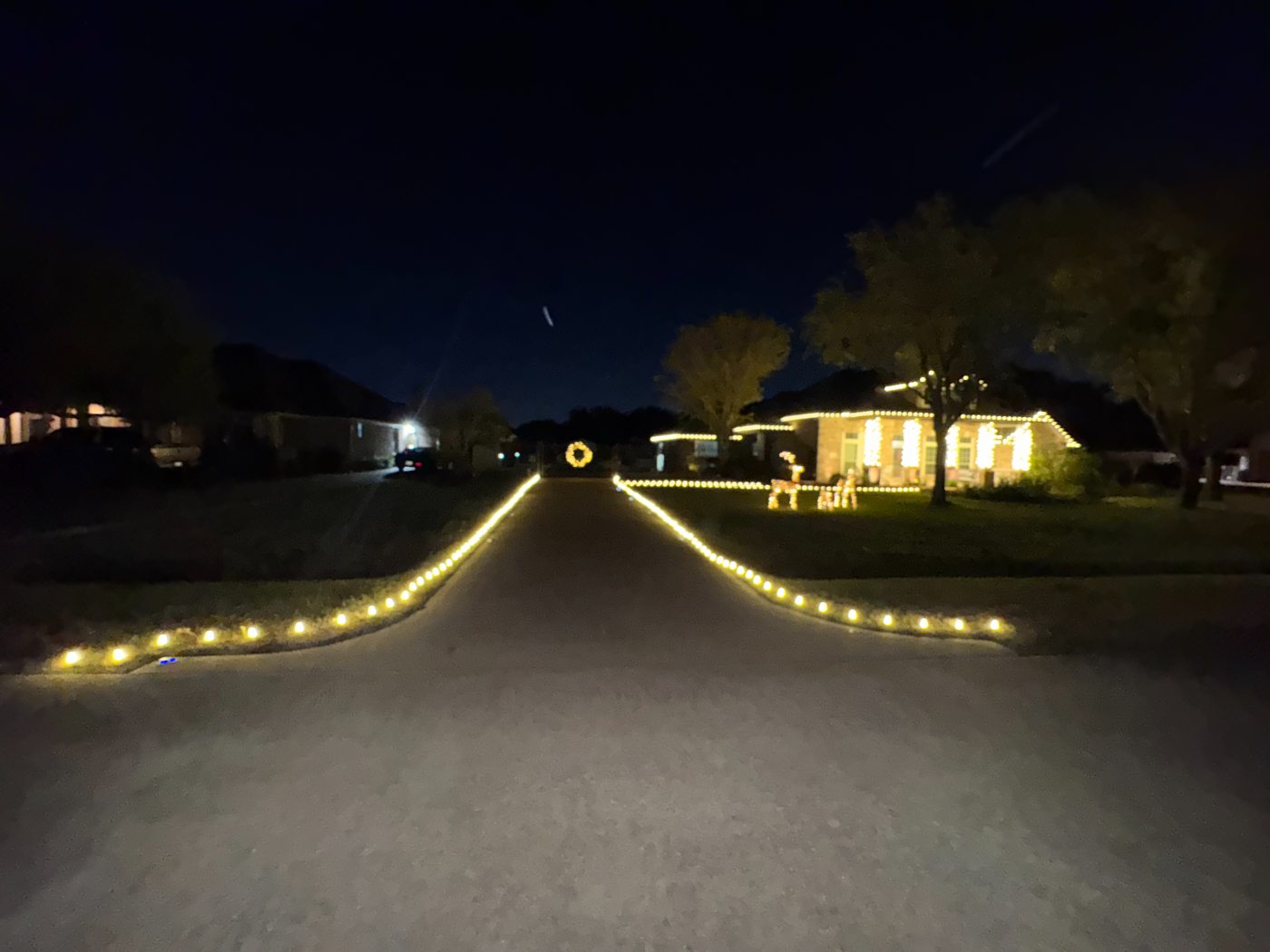 Driveway outlined to the street with a lit wreath at the gate